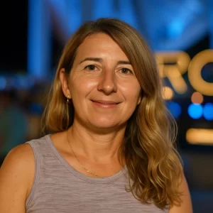 Sophia Russo, a smiling boutique owner in Berkley, standing at an evening event with festive lighting in the background.